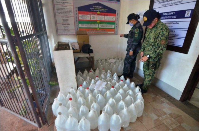 SEIZED ALCOHOL. Police officers check these plastic containers of alcohol seized from a group in an entrapment operation in Iloilo City. The group is suspected of selling alcohol at an overprice at a time when the city is battling to stop the spread of the coronavirus disease 2019. IAN PAUL CORDERO/PN