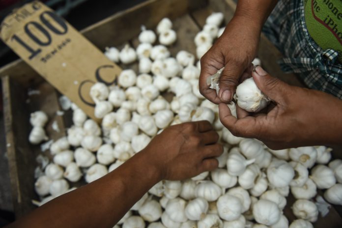 A vendor prepares garlic for sale at a public market in Manila. ABS-CBN NEWS