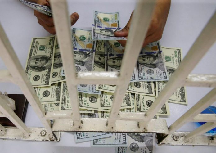 A worker counts U.S. dollar bills inside a money changer in Metro Manila