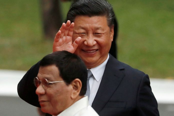 Chinese President Xi Jinping waves to the media as he walks with Philippine President Rodrigo Duterte before their one on one meeting at the Malacanang presidential palace in Manila, Philippines, November 20, 2018.