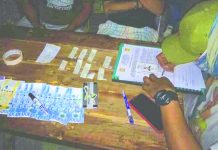 An antidrug personnel examines the suspected shabu and drug paraphernalia seized from Andre Mabasa after he sold illegal drugs to a poseur-buyer in Kalibo, Aklan on June 27. PDEA REGION 6