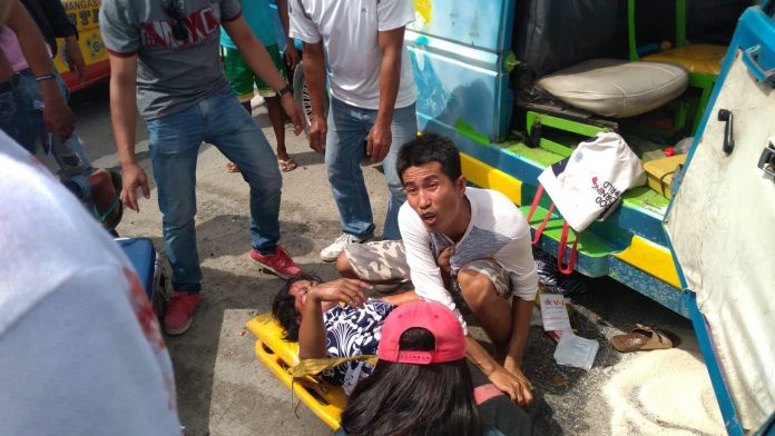 COLLISSION. This man helps a lady who got injured when a passenger jeepney crashed against a car on the coastal road in Barangay Dacutan, Dumangas, Iloilo on Tuesday afternoon, June 25. IAN PAUL CORDERO/PN