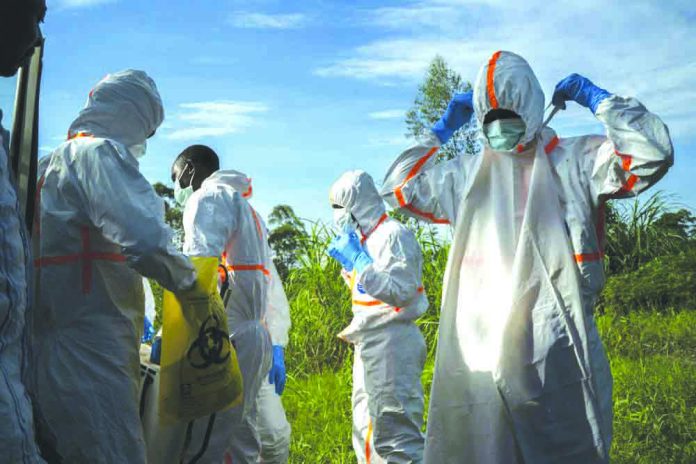 In this Sunday, July 14, 2019 photo, burial workers put on protective gear before carrying the remains of Mussa Kathembo, an Islamic scholar who had prayed over those who were sick, and his wife, Asiya, to their final resting place in Beni, Congo. AP