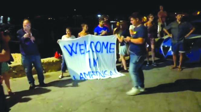 Italy rebuffs German migrant appeal People hold a banner reading “Welcome in Lampedusa” as migrants disembark a rescue boat in the port of Lampedusa, Italy, July 7, 2019, in this still image taken from video footage. REUTERS