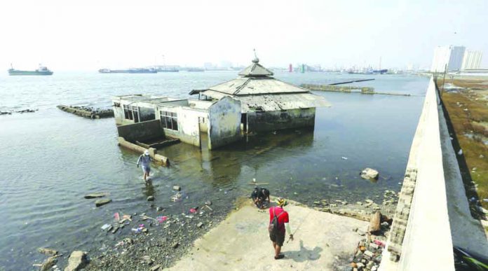 Jakarta Sea Wall People walk near a giant sea wall which is used as a barrier to prevent sea water from flowing into land and cause flooding in Jakarta, Indonesia, Saturday, July 27, 2019. Indonesia's President Joko Widodo said in an interview that he wants to see the speedy construction of the giant sea wall to save the low-lying capital of Jakarta from sinking under the sea. AP