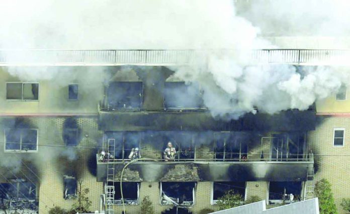 Firefighters work as smoke billows from a three-story building of Kyoto Animation in a fire in Kyoto, western Japan, Thursday, July 18, 2019. Kyoto prefectural police said the fire broke out Thursday morning after a man burst into it and spread unidentified liquid and put fire. Kyodo News via AP