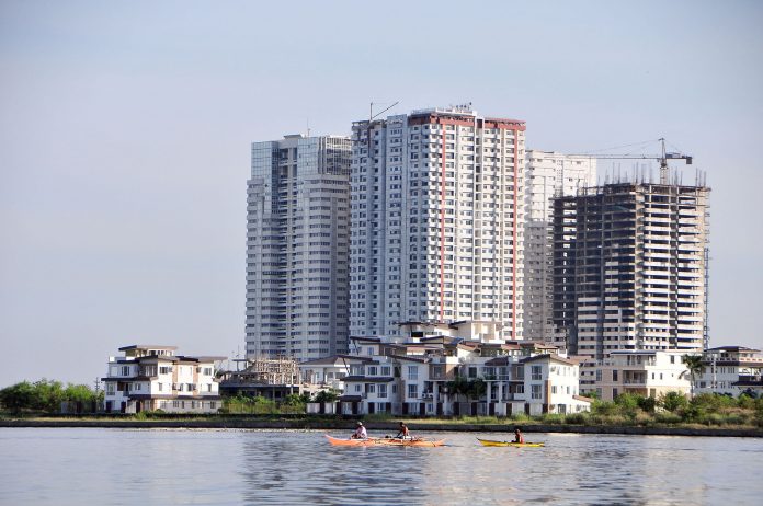 Filipino Fisherfolk Under Threat From Commercial Fishers & Real estate Development Plans Local fishermen paddle past residential condominiums and townhouses in Metro Manila. GETTY IMAGES