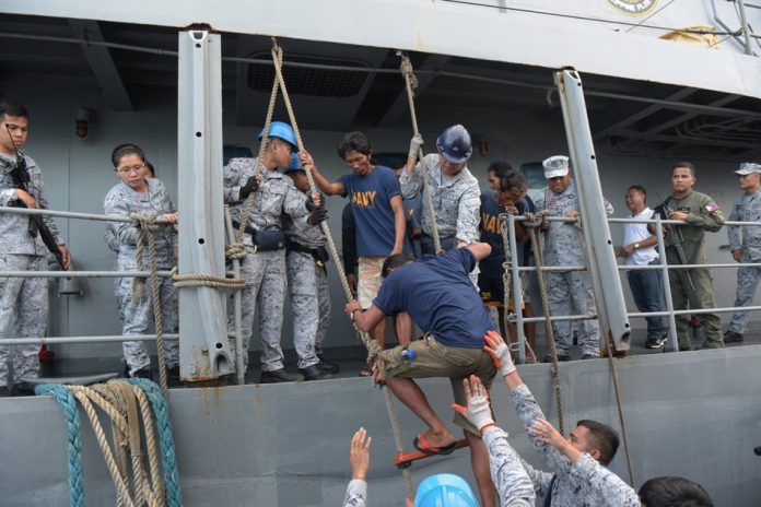 Filipino fishermen who were rescued after their fishing boat was hit by a Chinese vessel transfer to another ship as they head back to Occidental Mindoro on June 14, 2019. AP