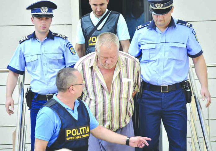 World Romania Police officers escort Gheorghe Dinca, the suspect in the case of rape and murder of a 15-year-old girl, from a court in Craiova, southern Romania, Saturday, July 27, 2019. AP