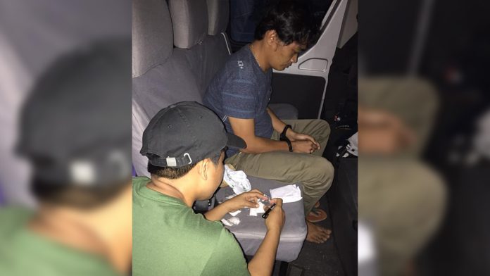 Drug suspect Carlo Boncalon (left) sits handcuffed after police officers arrested him in an entrapment operation in Barangay 10, Bacolod City on Aug. 26. PDEA REGION VI – WESTERN VISAYAS
