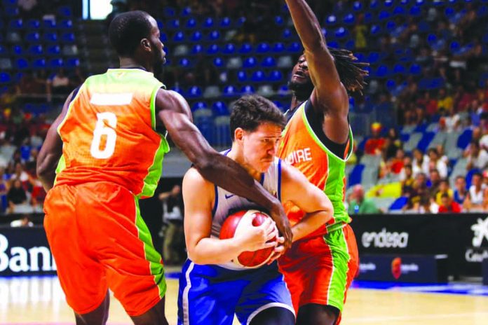 Gilas Pilipinas’ Robert Bolick Jr. tightened his grip on the ball after being trapped by two Ivory Coast defenders. PHOTO COURTESY OF CIGNAL-SBP