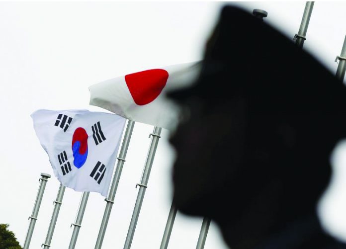 Korea Japan A police officer stands guard near Japan and South Korea national flags at a hotel, where the South Korean embassy in Japan is holding the reception to mark the 50th anniversary of the normalisation of ties between Seoul and Tokyo, in Tokyo June 22, 2015. REUTERS