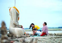 Drought reveals lost temple in Thailand submerged by dam A family prays near the ruins of a headless Buddha statue, which has resurfaced in a dried-up dam due to drought, in Lopburi, Thailand August 1, 2019. REUTERS