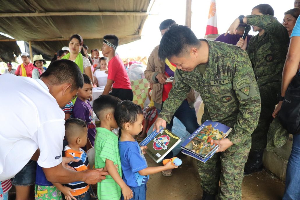 While an officer hands free books to students of the Supanga Elementary School. 61IB/PIA