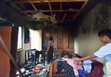 An officer of the Bureau of Fire Protection checks a house struck by fire in Barangay Cubay, Jaro district on Friday. IAN PAUL CORDER/PN