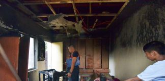 An officer of the Bureau of Fire Protection checks a house struck by fire in Barangay Cubay, Jaro district on Friday. IAN PAUL CORDER/PN
