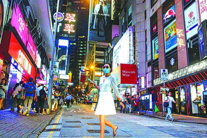 Hong Kong, China A woman crosses a street in the Central business district in Hong Kong, China Aug. 22, 2019. China plans to provide more support for its economy, including investing in infrastructure projects and regional development, while maintaining a prudent monetary policy. REUTERS
