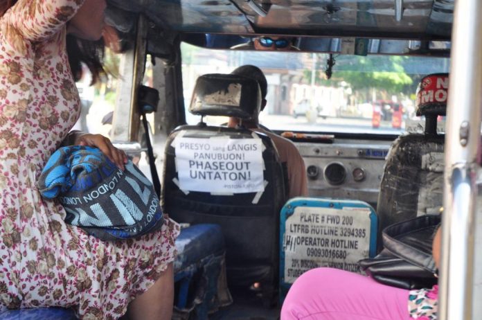 SILENT PROTEST. A poster at the back of this jeepney driver’s seat expresses his sentiment on the planned scrapping of old jeepneys and the incessant fuel price hikes. PN PHOTO