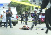 In this June 2, 2019 file photo, the body of a bloodied man lies in the middle of a street where police and forensic workers secure the crime scene in Acapulco, Mexico.