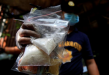 A member of the Philippine National Police investigation unit shows confiscated methamphetamine, known locally as shabu, along with Philippine peso bills seized from suspected drug pushers during an operation by the police in Quiapo, Manila on July 3, 2016. REUTERS