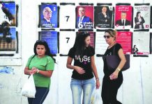 Tunisia seeks new leader to boost economy, fight terror Women walk past candidates' posters and designated numbers a day before the start of presidential election in Tunis, Tunisia, Saturday, Sept. 14, 2019. AP