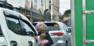 BEGGING FOR HELP.Carrying a baby, a Badjao beggar knocks on the window of a vehicle stuck in traffic in Barangay Ungka, Jaro, Iloilo City. The city government plans to transport back to Sulu all Badjao mendicants. Also called “sea gypsies”, many Badjaos have been displaced by decades of conflict in Mindanao. IAN PAUL CORDERO