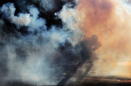 A demonstrator runs amid tear gas during a protest against the country’s state economic model in Santiago, Chile on Oct. 22. REUTERS/IVAN ALVARADO