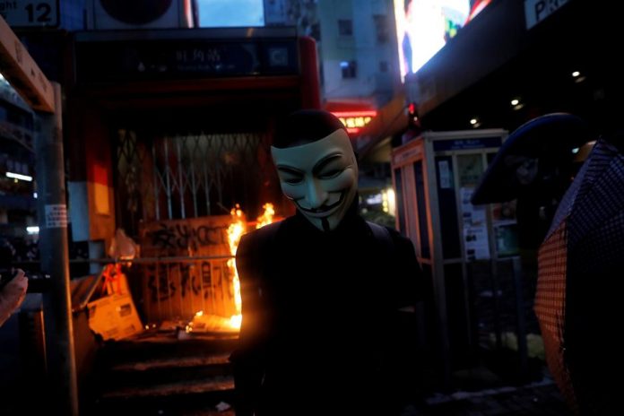 A masked anti-government protester leaves after helping to set a fire at the entrance of a metro station in Hong Kong, China on Oct. 6. REUTERS/SUSANA VERA
