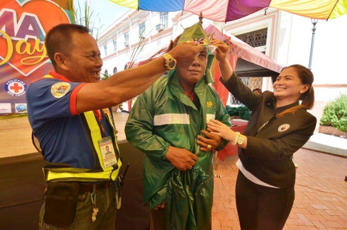 FOR SERVICE, RAIN OR SHINE. Iloilo City’s Rep. Julienne “Jam” Baronda helps a traffic aide put on a raincoat. A total of 291 traffic aides received rain protective gears from the city’s first congresswoman to shield them from inclement weather while on duty. IAN PAUL CORDERO/PN