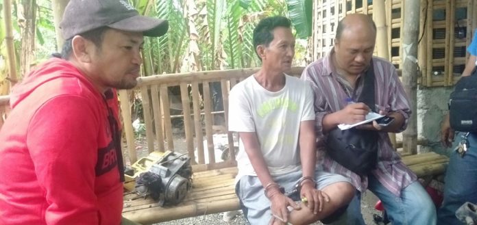 Jimmy Ramos (second from right) sits handcuffed after he was arrested for illegal possession of firearm in Barangay Jalas, New Washington, Aklan last week. RADYO TODO/PN