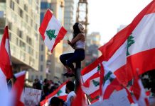 ‘Lebanon could sink like Titanic’ A demonstrator sits on a pole while carrying a national flag during an anti-government protest in downtown Beirut, Lebanon on Oct. 20. REUTERS/ALI HASHISHO