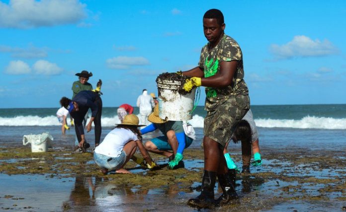 A man works to remove an oil spill on Muro Alto beach in Tamandaré, Pernambuco, Brazil. REUTERS