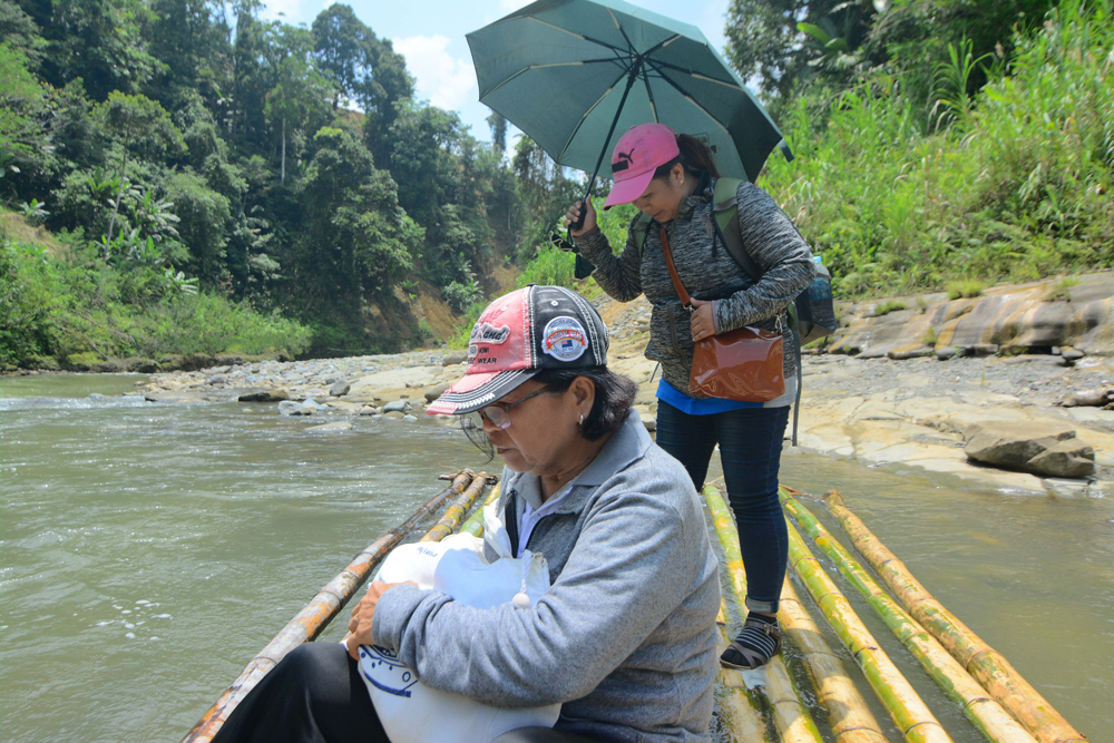 A bamboo raft keeps the teachers from getting wet when crossing a deep portion of this river