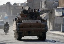 Turkey-backed Syrian rebel fighters are seen on a military vehicle in the town of Tal Abyad, Syria on Oct. 13. REUTERS/KHALIL ASHAWI