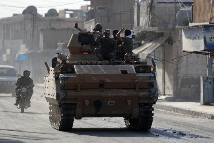 Turkey-backed Syrian rebel fighters are seen on a military vehicle in the town of Tal Abyad, Syria on Oct. 13. REUTERS/KHALIL ASHAWI