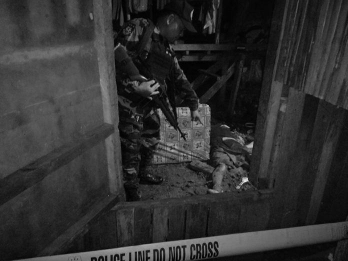 An officer points at the lifeless body of resident Lito Bawa-an, who was hacked and stabbed to death, in Barangay San Jose, Sipalay City, Negros Occidental on Nov. 21. SIPALAY CITY POLICE STATION