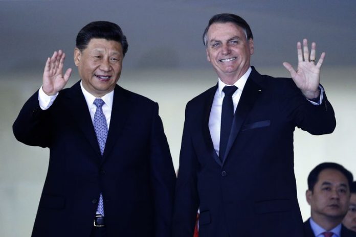China’s President Xi Jinping, left, and Brazil’s President Jair Bolsonaro wave to reporters upon Xi Jinping’s arrival for a bilateral meeting on the sidelines of the 11th edition of the BRICS (Brazil, Russia, India, China and South Africa) Summit, at the Itamaraty Palace in Brazil, on Nov. 13. ERALDO PERES/AP PHOTO