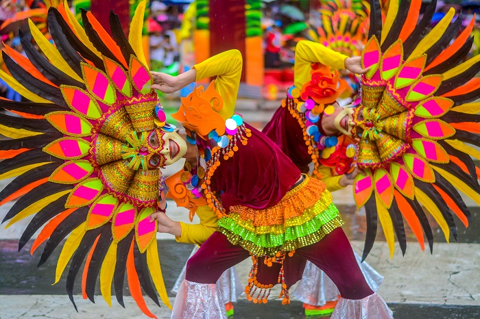 The unwavering smiles on the masks of Ruby MassKara Festival dancers stand out in the middle of a heavy rain.