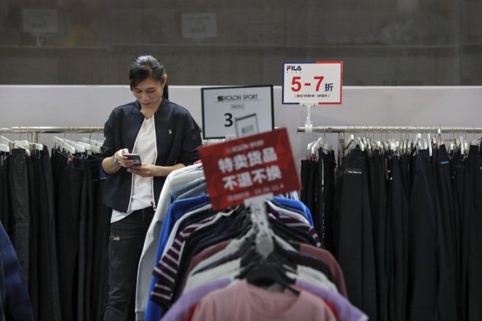 Phone China An employee browses through her smartphone at a shopping mall in Shenzhen, China’s Guangdong province. China has raised the estimate of its economy size by 2.1 percent following a census, raising its gross domestic product for 2018 to 91.93 trillion yuan ($13.1 trillion). ANDY WONG /AP