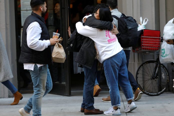 WeWork employees embrace on the sidewalk outside the entrance to the WeWork corporate headquarters in Manhattan, New York WeWork employees embrace on the sidewalk outside the entrance to the WeWork corporate headquarters in Manhattan, New York, U.S., November 21, 2019. MIKE SEGAR/REUTERS