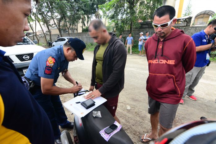 Police officers inspect items recovered from Gidney Boy Torrato. Torrato was nabbed in entrapment operation after he sold a sachet of suspected marijuana to a poseur-buyer on Dec. 17. IAN PAUL CORDERO/PN