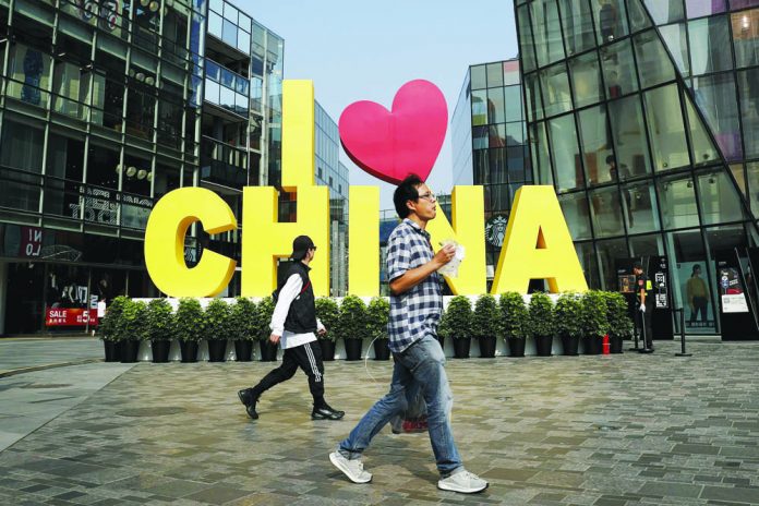 I love China A man eats a snack while passing an “I love China” decoration at a popular shopping mall in Beijing. China put a positive face Saturday on a first-step trade agreement that dials down a trade war it blames the United States for starting. AP