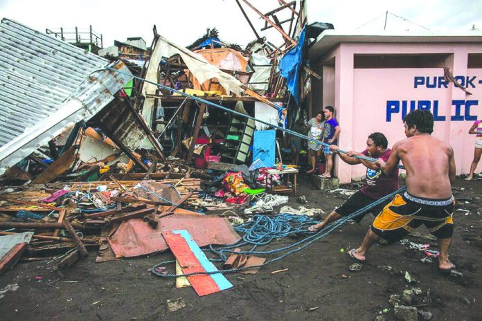 Tisoy PH Workers repair damaged houses along the coastline in the aftermath of Typhoon Tisoy in Legazpi City, Albay on Tuesday. Tisoy brought heavy rains and strong winds as it made its first landfall on Monday evening in Sorsogon province. BASILIO SEPE/GREENPEACE