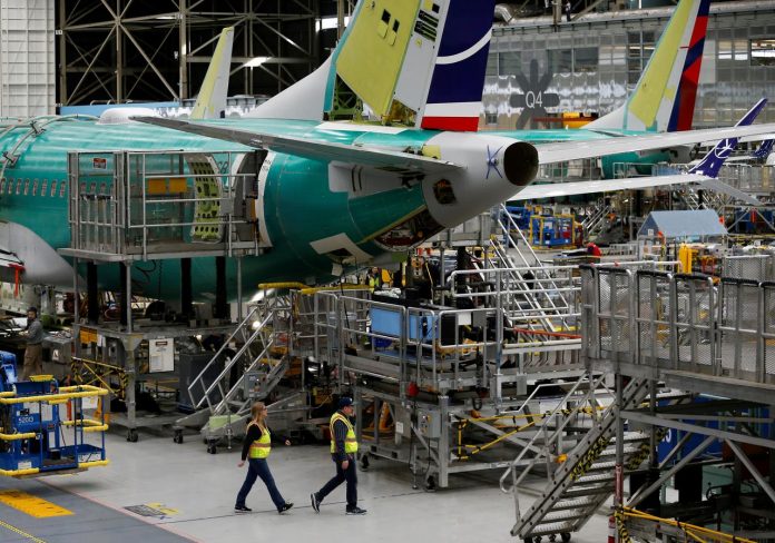 Employees walk by the end of a 737 Max aircraft at the Boeing factory in Renton, Washington, United States. REUTERS