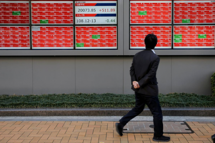 Asian shares A man looks at an electronic board showing the Nikkei stock index outside a brokerage in Tokyo, Japan. REUTERS