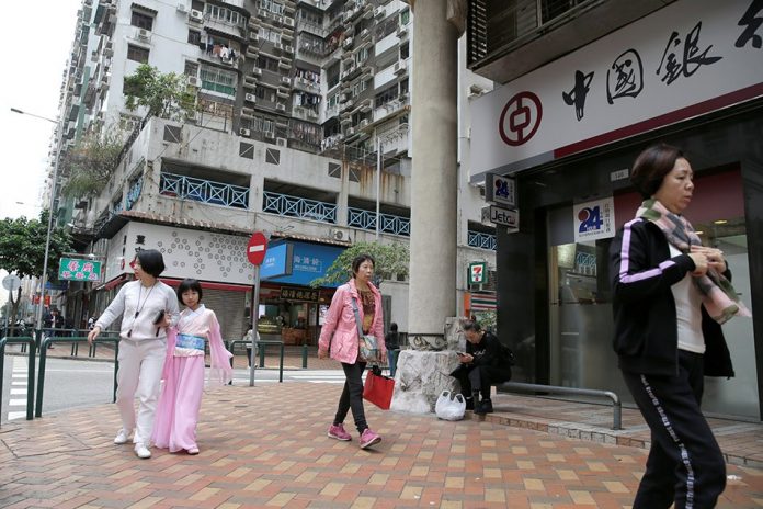 China People walk past a Bank of China branch in Macau, China Dec. 19, 2019. China’s central bank was cutting the reserve requirements for banks, freeing up about $114 billion to boost lending and spur the slowing economy. REUTERS