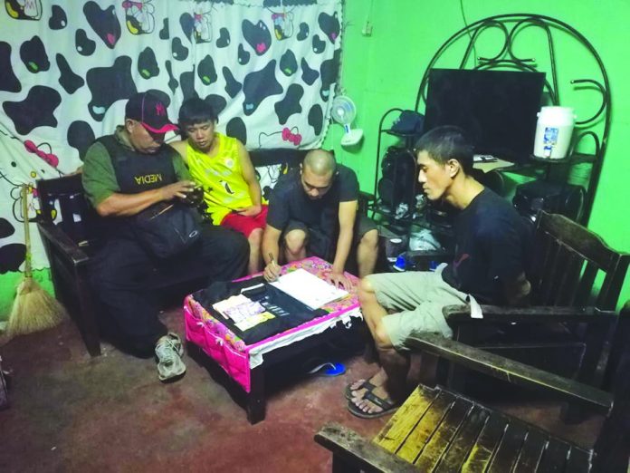 Hernan De Asis Antidrug officers inspect items confiscated from Hernan De Asis in a buy-bust operation in Barangay 27 on Monday. POLICE STATION 4/ BCPO