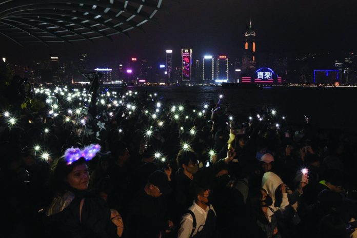Hong Kong protest Pro-democracy protesters and people gather at the promenade of Tsim Sha Tsui district as they light up their phones to celebrate the New Year’s Eve, in Hong Kong on Dec. 31, 2019. REUTERS