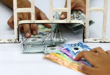 Peso dives to record low; stocks tumble nearly 5% Hand holding a fanned stack Philippine banknotes being exchanged for dollars.