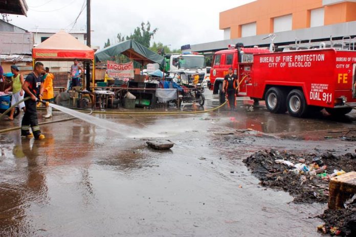 region Bacolod An officer of the Bureau of Fire Protection sprays water on a road cleared of erring structures. Recently, the Department of the Interior and Local Government in Bacolod City reminded village officials of their roles to sustain the city’s gains during the 60-day road-clearing operations. CONTRIBUTED PHOTO/PN